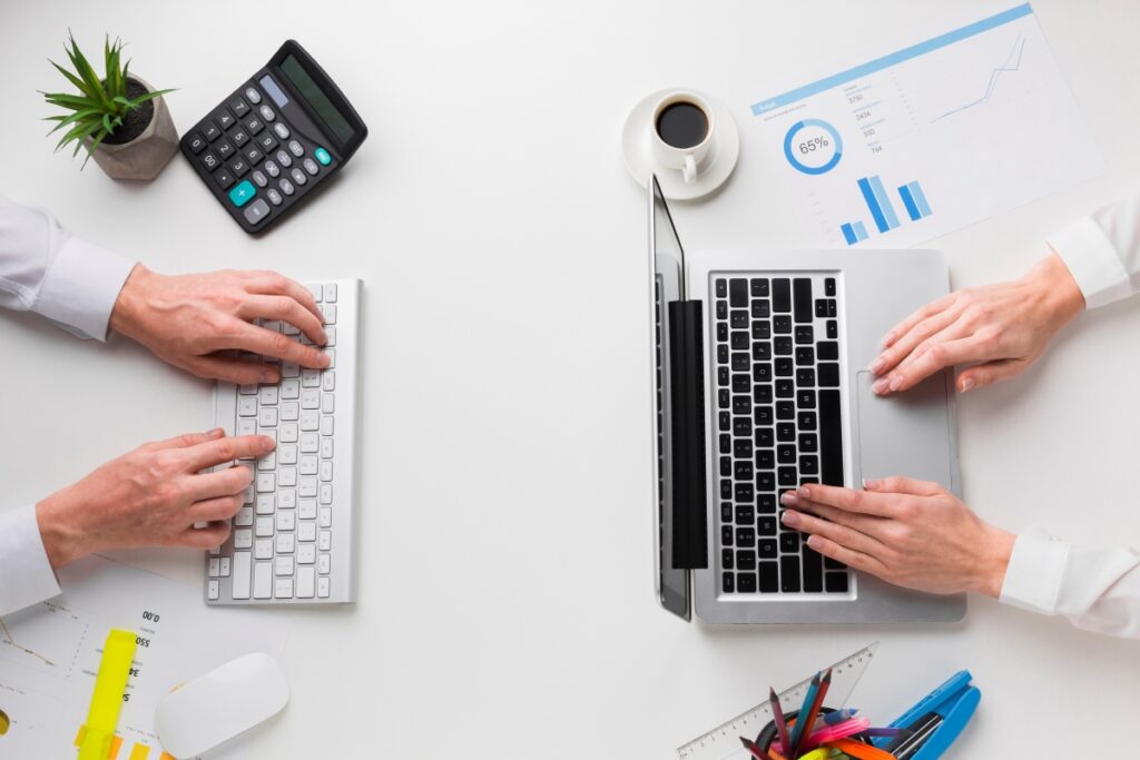 top-view-desk-with-hands-working-laptop-keyboard