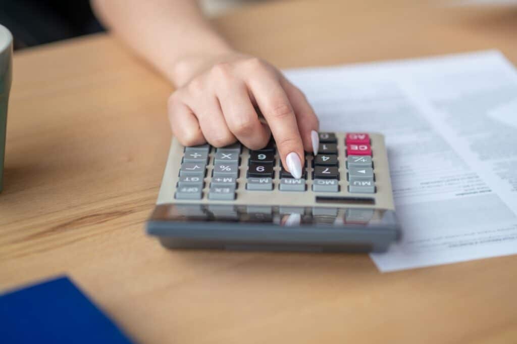 bookkeeper-seated-office-desk-using-pocket-calculator