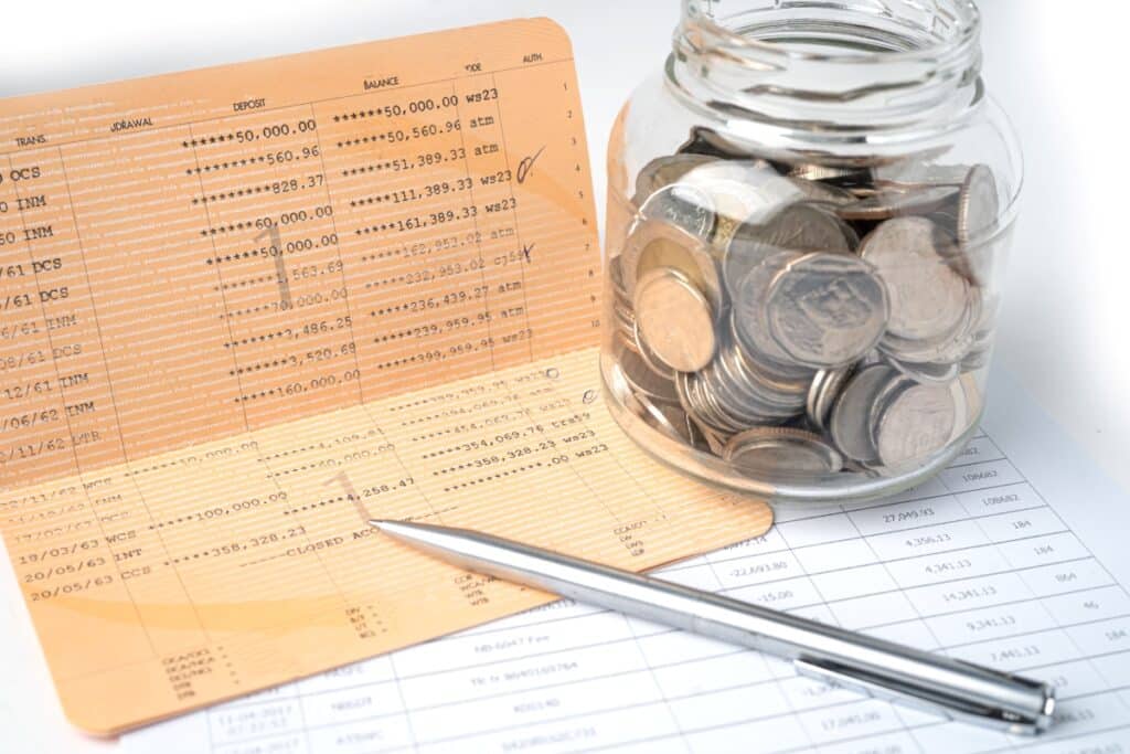 pen-on-account-book-bank-with-coins-in-glass-jar-banking